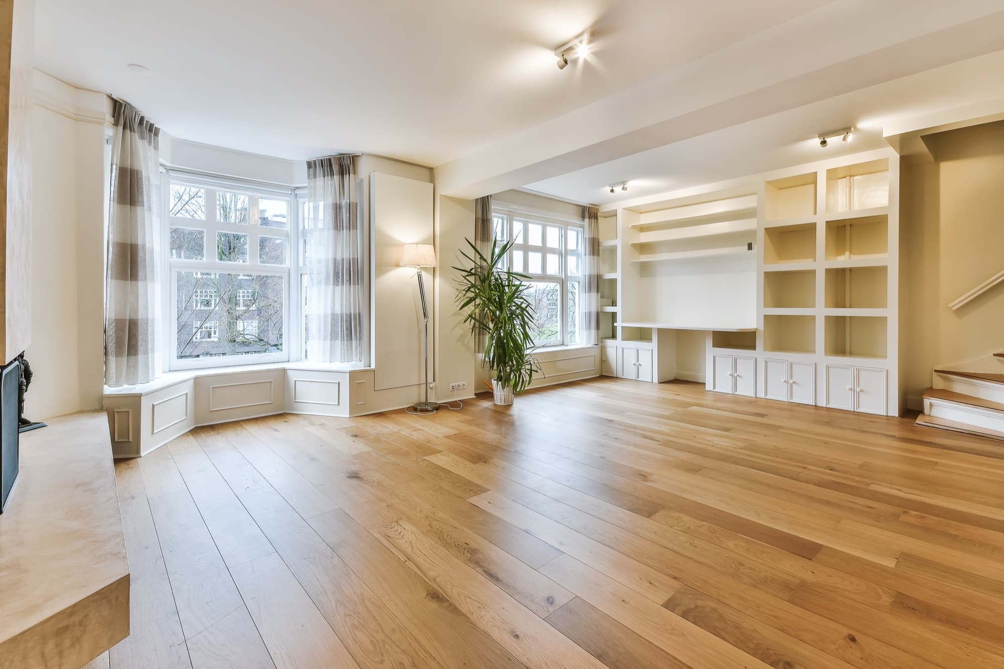 Wide-plank oak flooring running through a bright reception room with a bay window