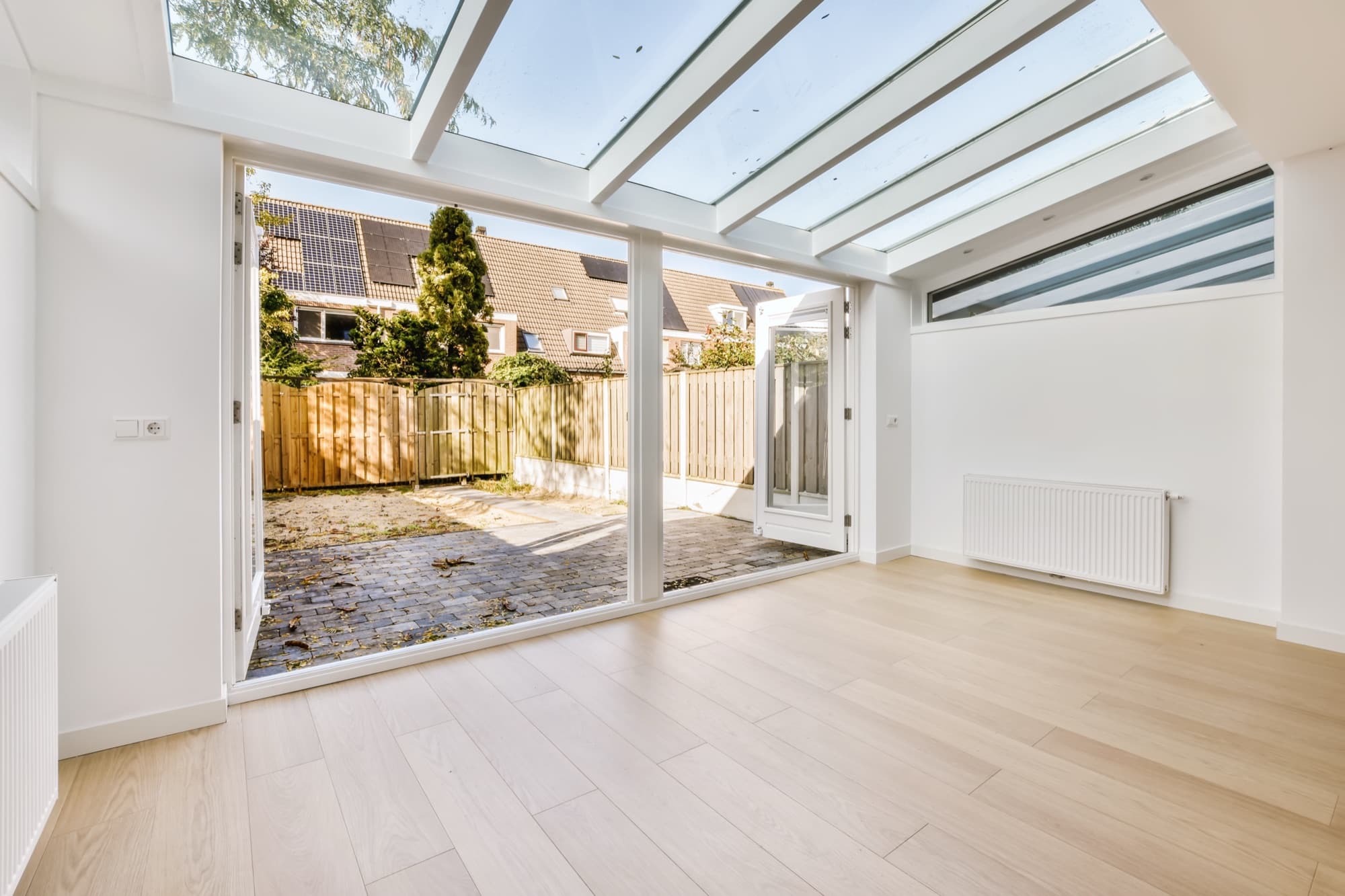Glazed rear extension with a pitched glass roof and sliding doors opening onto a paved garden