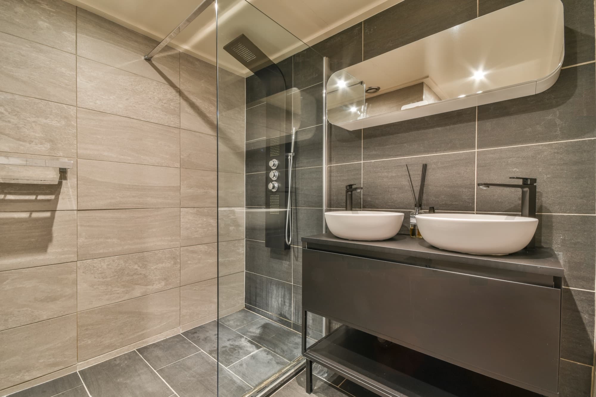Modern cloakroom finished in dark tiling with feature lighting
