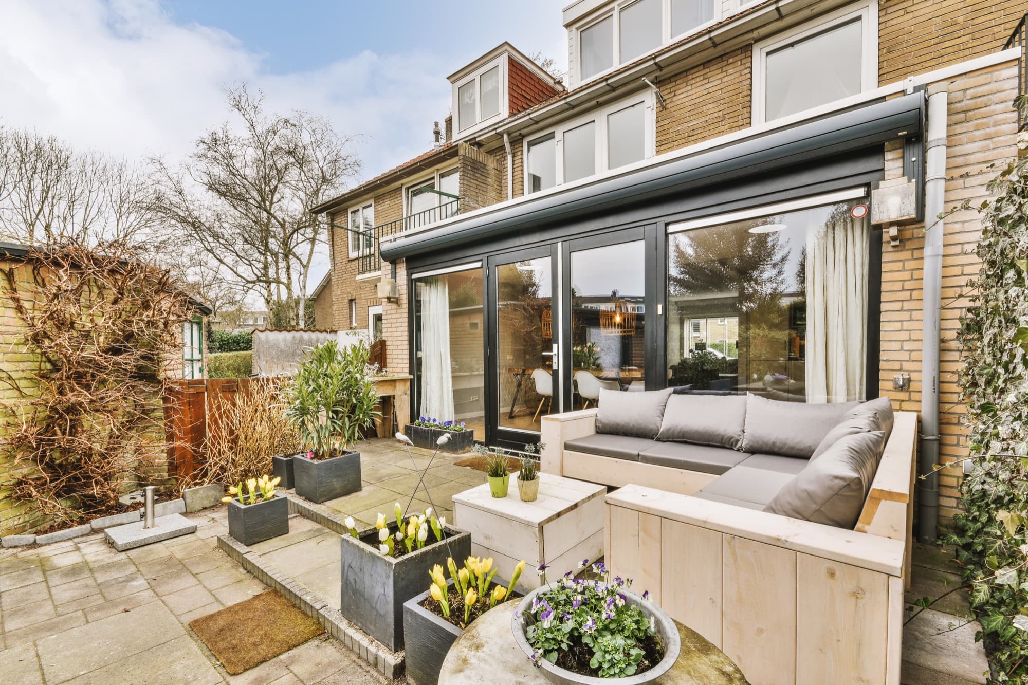 Paved patio with built-in timber seating outside sliding doors to a garden room